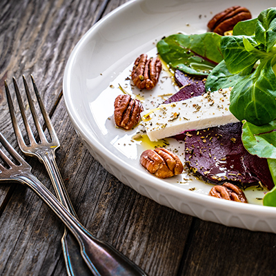 Leckerer Salat mit Walnüssen auf einem Teller mit Besteck